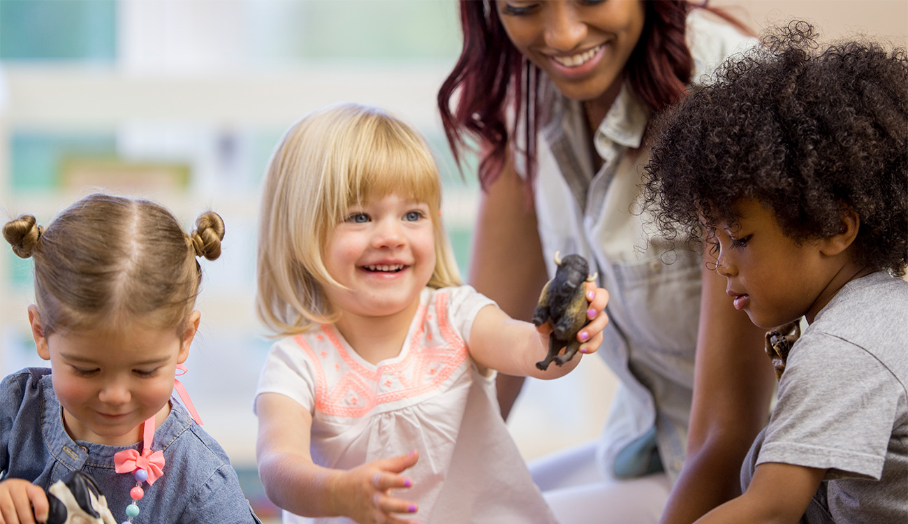 Toddlers sharing toys together with a home child care provider